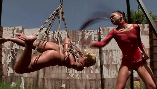 Sophisticated domina puts clothing pegs on curvy blondie in BDSM video porn pics